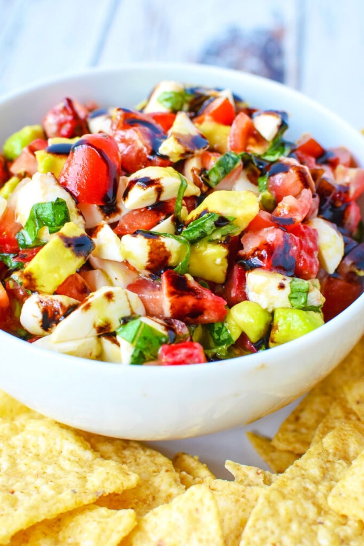 white bowl with strawberry caprese salad and tortillas.