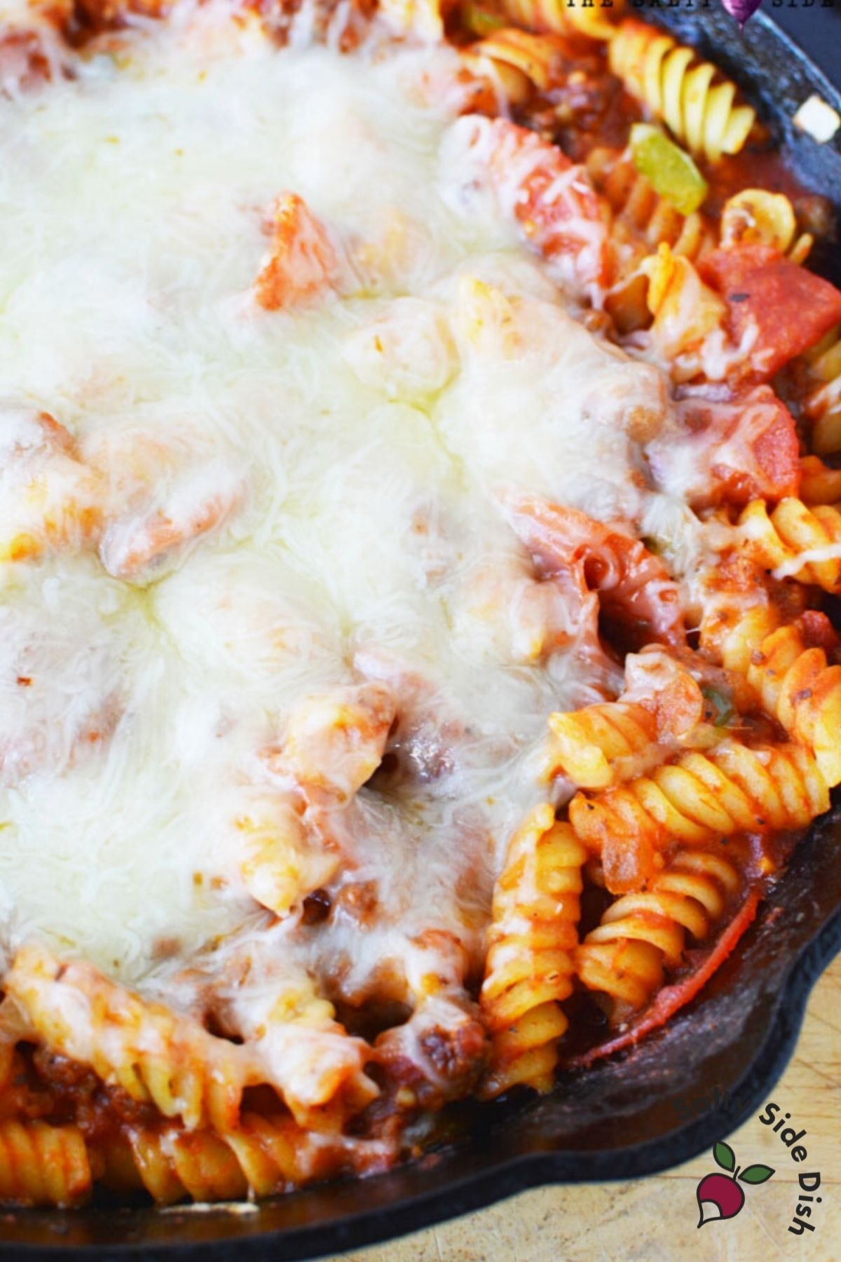 plate of cheesy pizza casserole in a cast iron pan.