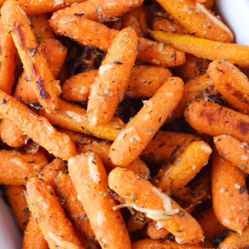 close up of parmesan roasted baby carrots showing crispy texture and melted cheese