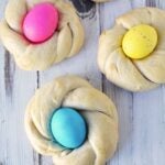 italian easter bread with bright colored easter eggs in center of pink, yellow, green, and blue.