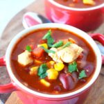red bowls that hold finished Mexican chicken chili with cilantro on top.