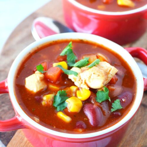 red bowls that hold finished Mexican chicken chili with cilantro on top.