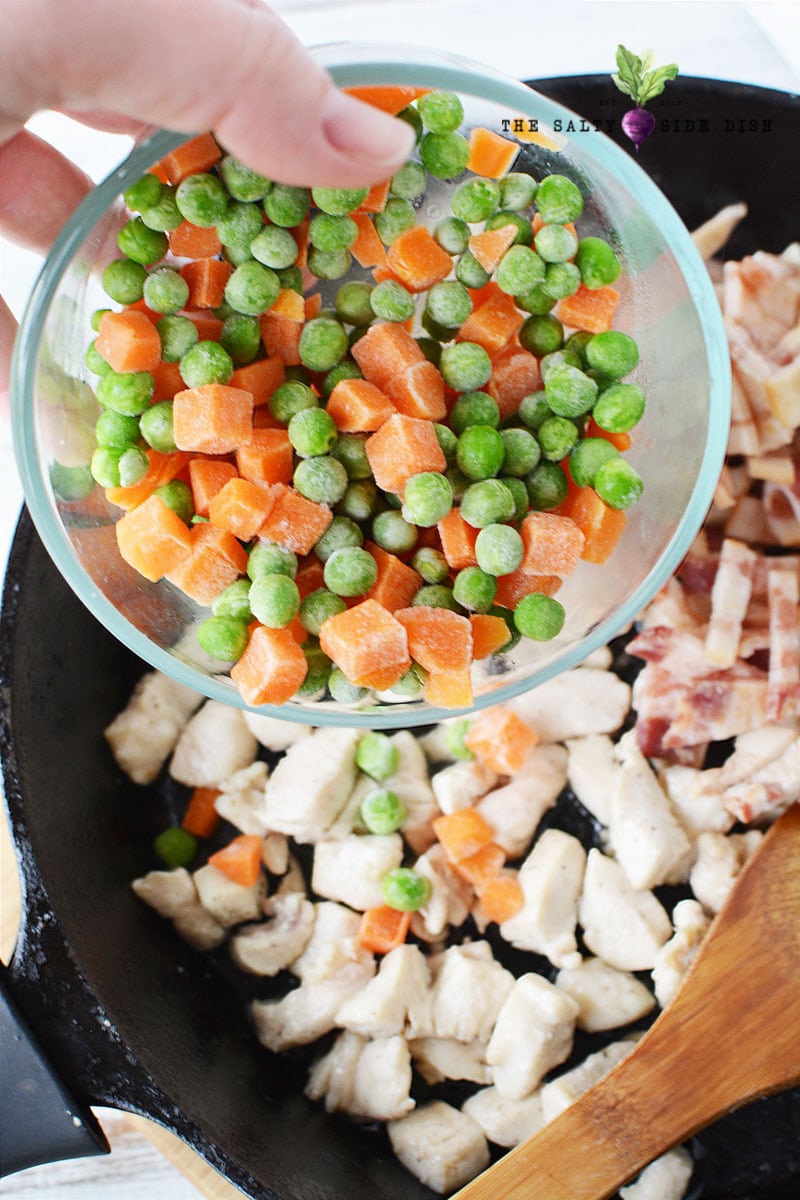 add frozen peas and carrots to your cast iron pan on top of cooked chicken and bacon