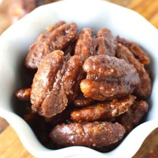 white bowl of candied pecans sitting on a wooden table