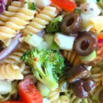 tri colored pasta salad with olives and tomatoes.