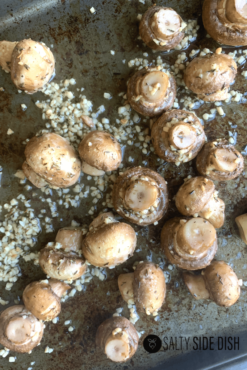 pan roasted white button mushrooms laying on sheet pan in garlic