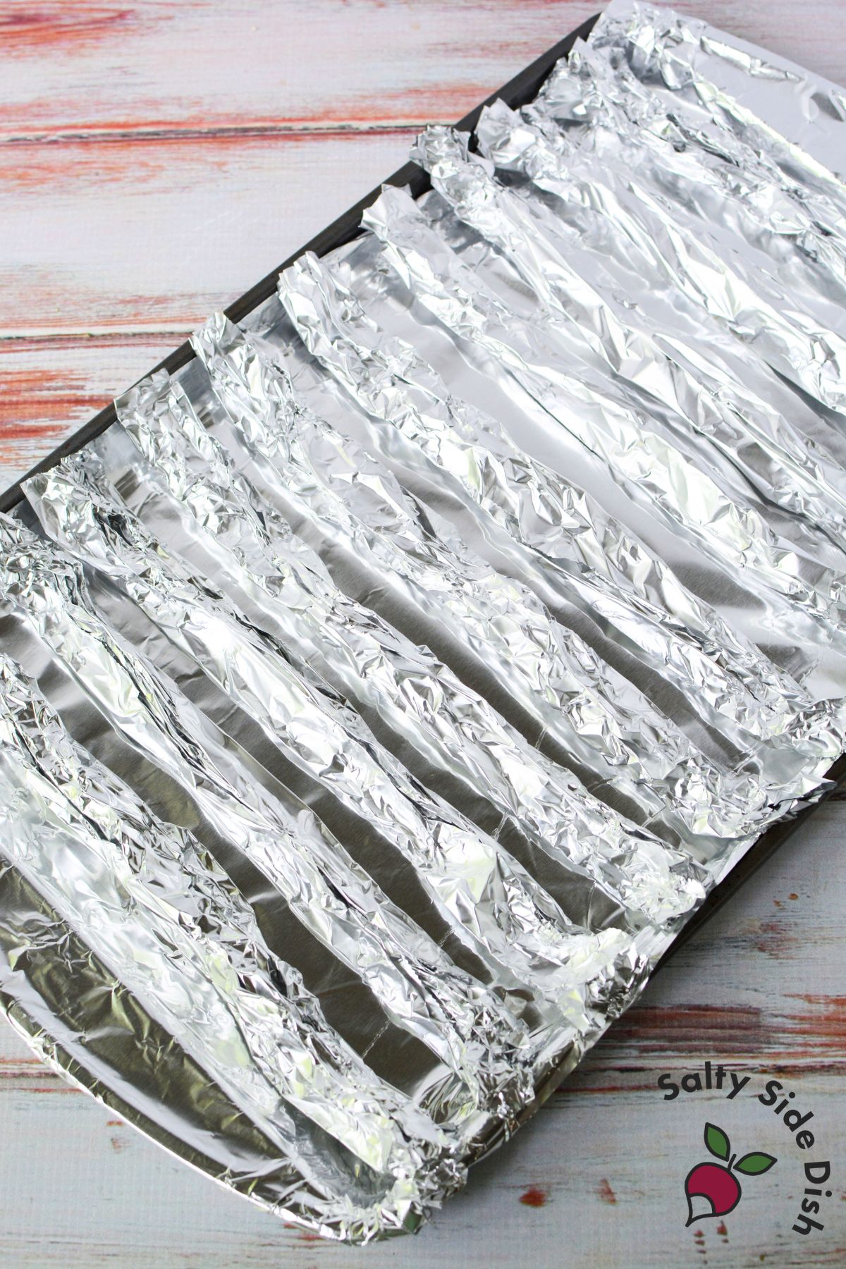 Rolled foil strip used as a DIY rack for cooking bacon in the oven
