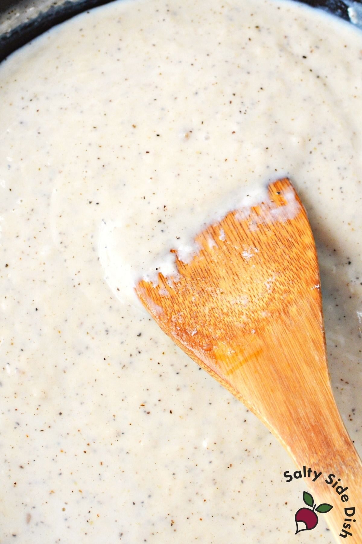 skillet with homemade gravy being stirred.