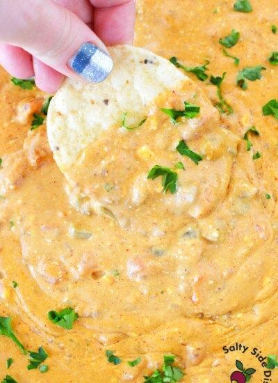 chili cheese dip with cream cheese and a chip dipping into it