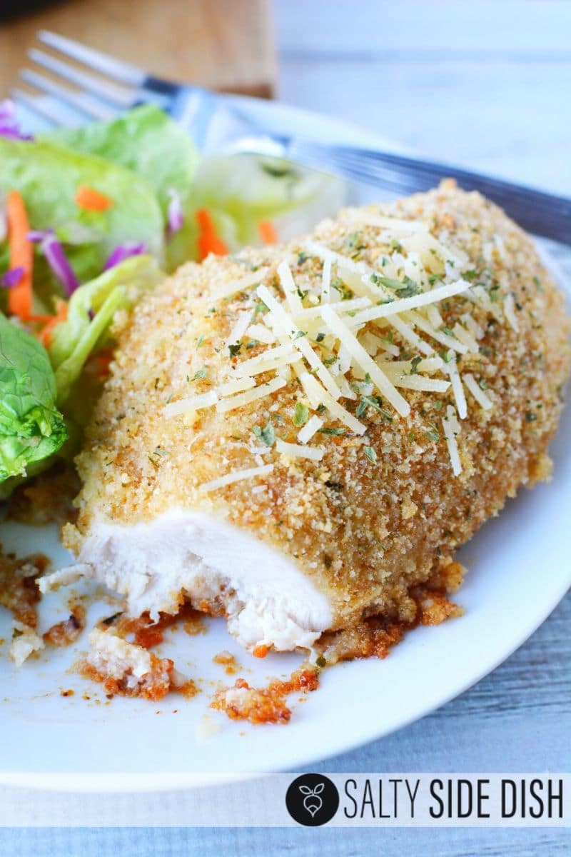 Easy Garlic Parmesan Chicken, baked in the oven, is a simple 30 minute chicken dinner recipe, topped with Parmesan Cheese and pairs great with most side dishes! #chickendinner #chickenbreastrecipes #garlicchicken chicken dinner cut into with garlic and extra Parmesan cheese