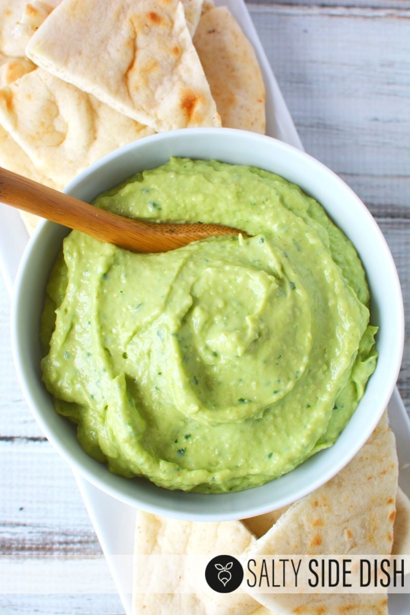 Avocado Tzatziki Dip in a white bowl with pita bread on the side
