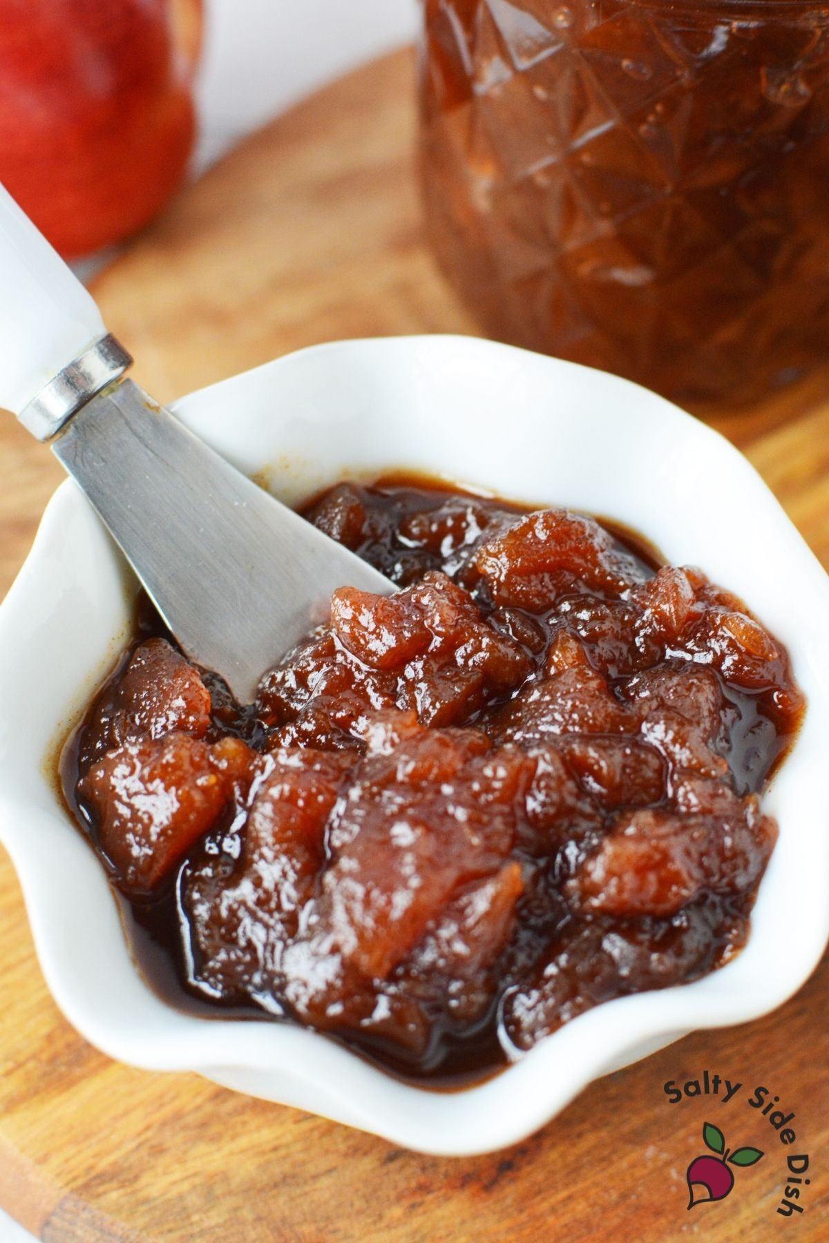 knife sitting in a chunky apple butter sauce, white bowl