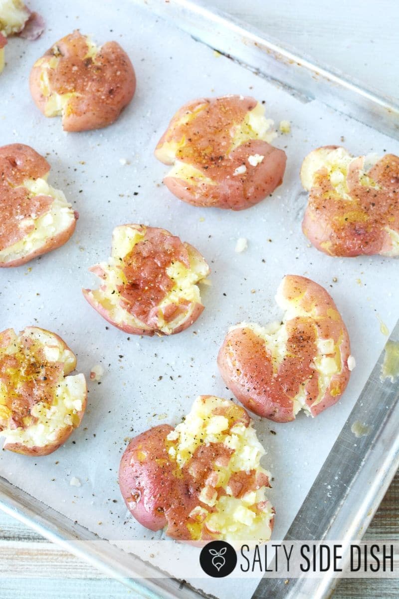 Seasoned and smashed potatoes without cheese sitting on a sheet pan