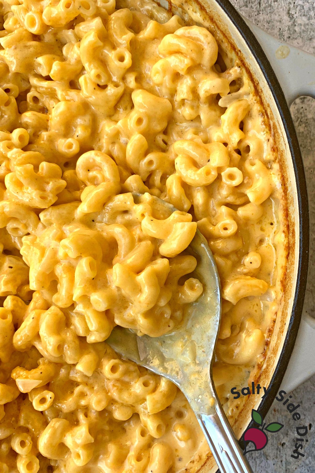 no boil macaroni and cheese recipe in a cast iron pan and large serving spoon.