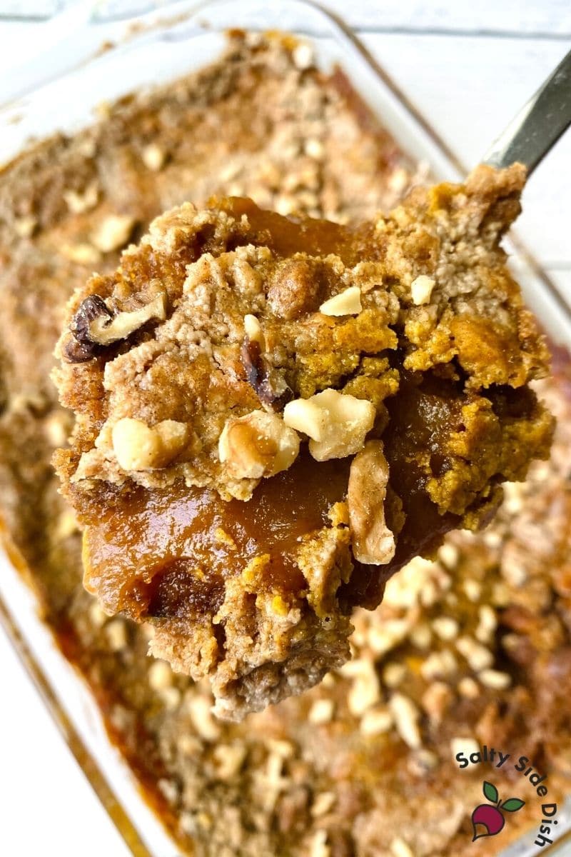 Pumpkin Pie Dump cake with spiced cake being scooped out with a bit of walnuts on top
