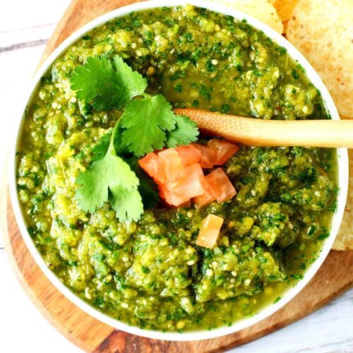 bowl of salsa verde with tomatoes and serving spoon