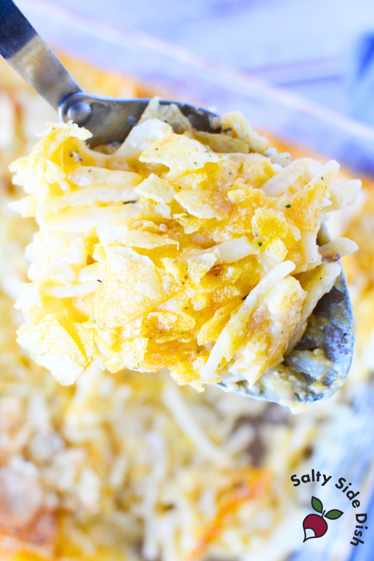 A spoonful of funeral potatoes with crispy chip topping and cheesy shredded hash browns