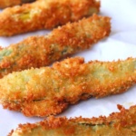 fried pickle spears on a paper towel draining.
