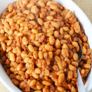 huge white plate of baked beans with a spoon sticking out of it