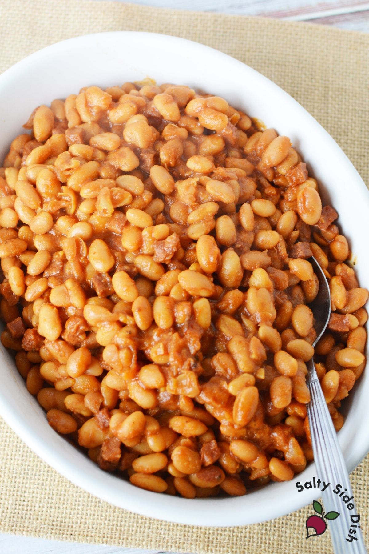 huge white plate of baked beans with a spoon sticking out of it