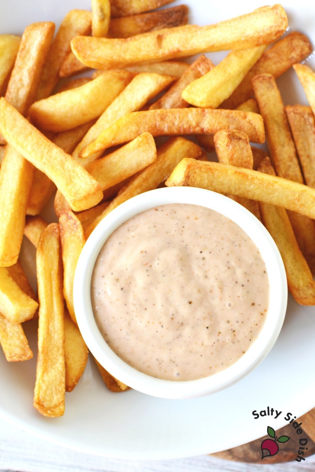 white plate with bowl of dipping sauce and fries on the side