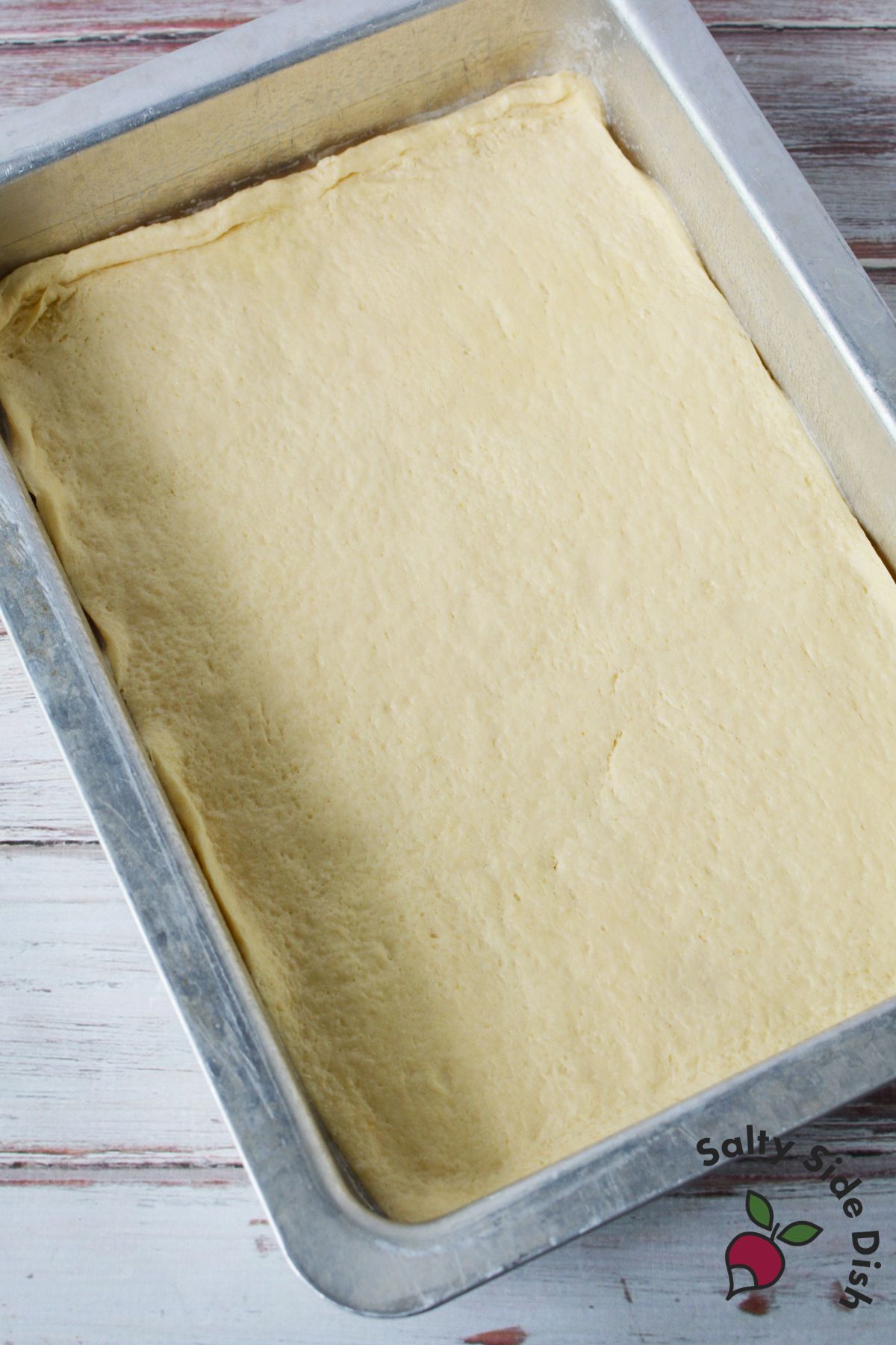 Pillsbury crescent roll sheet pressed into a baking pan for sopapilla cheesecake bars