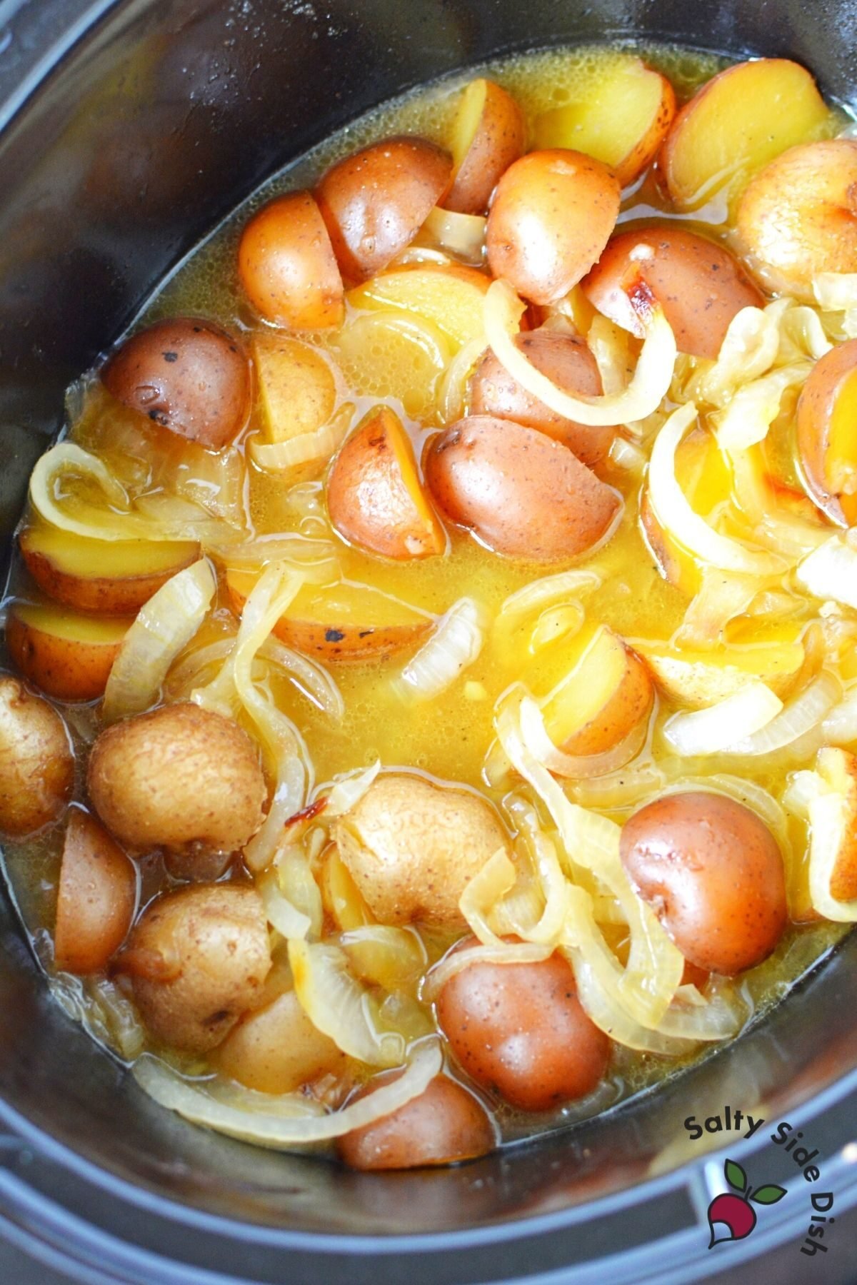 potatoes and onions in a black crockpot.