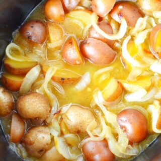 potatoes and onions in a black crockpot.