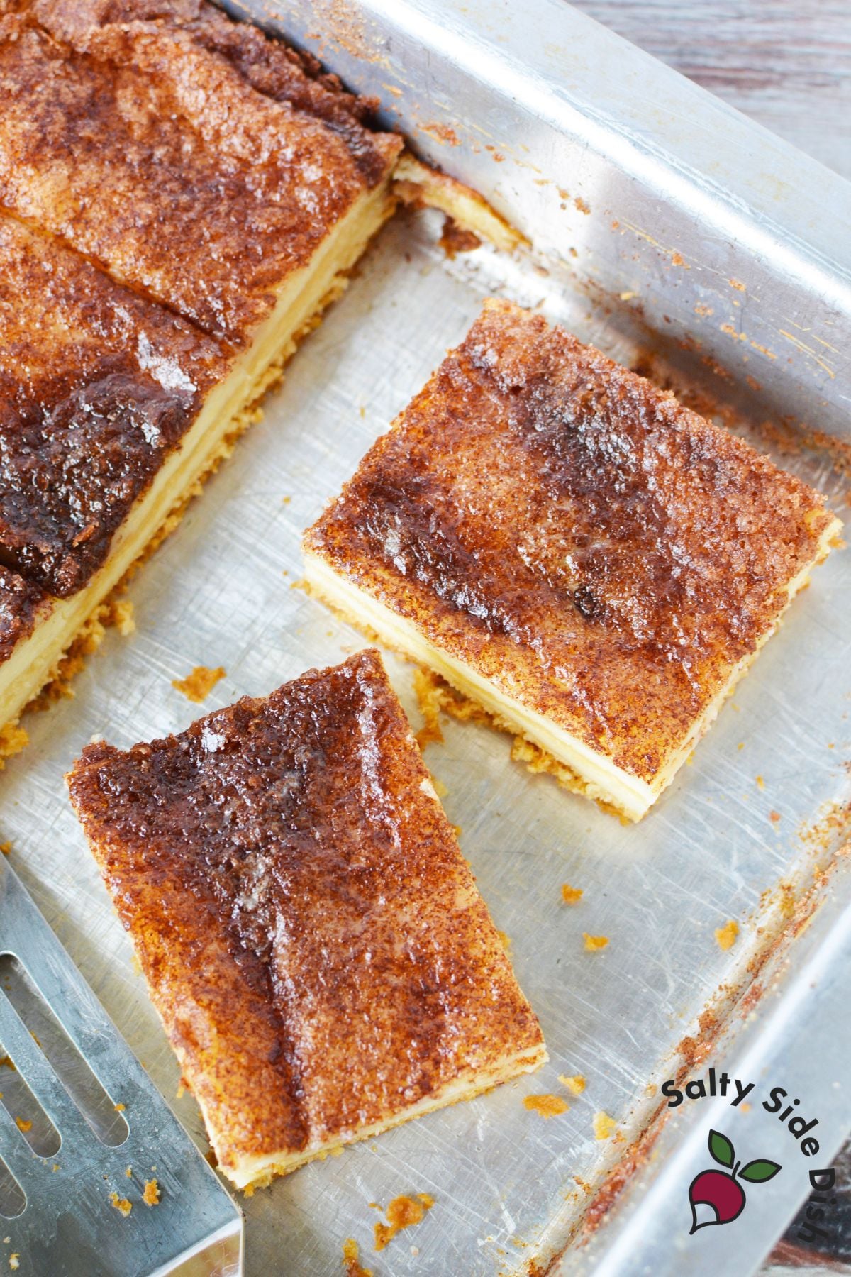 Baked sopapilla cheesecake bars cut into squares with a golden cinnamon sugar topping