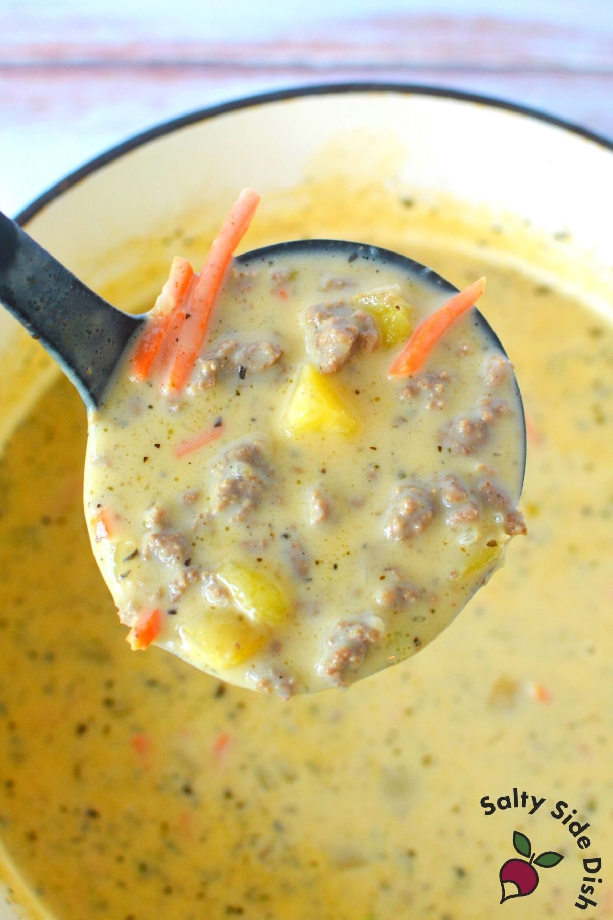 ladle dipping out a large scoop of creamy hamburger soup.