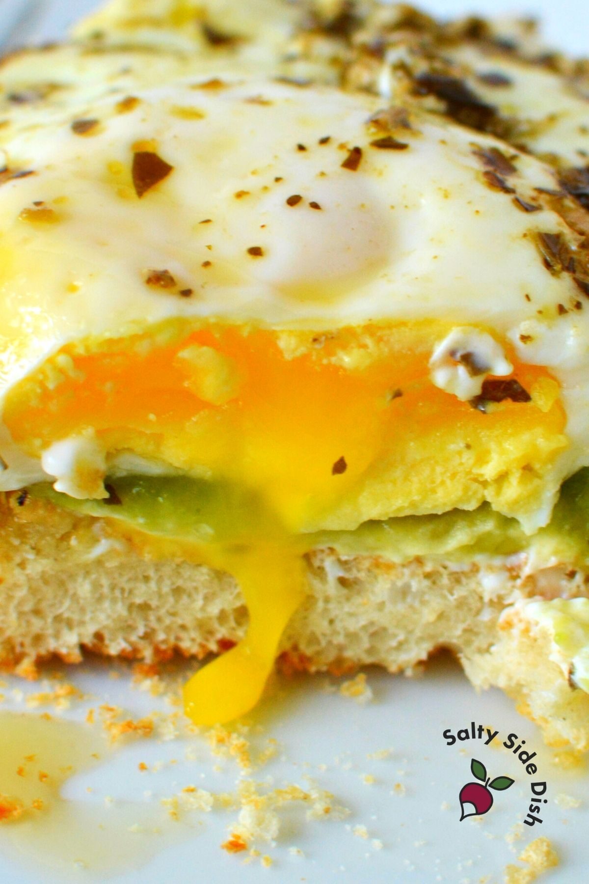 runny eggs on a sandwich with pesto and avocado.