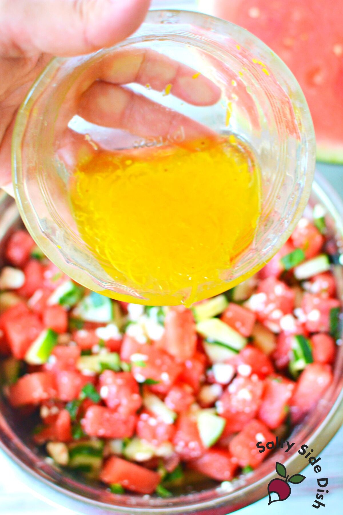 pouring dressing on watermelon salad.