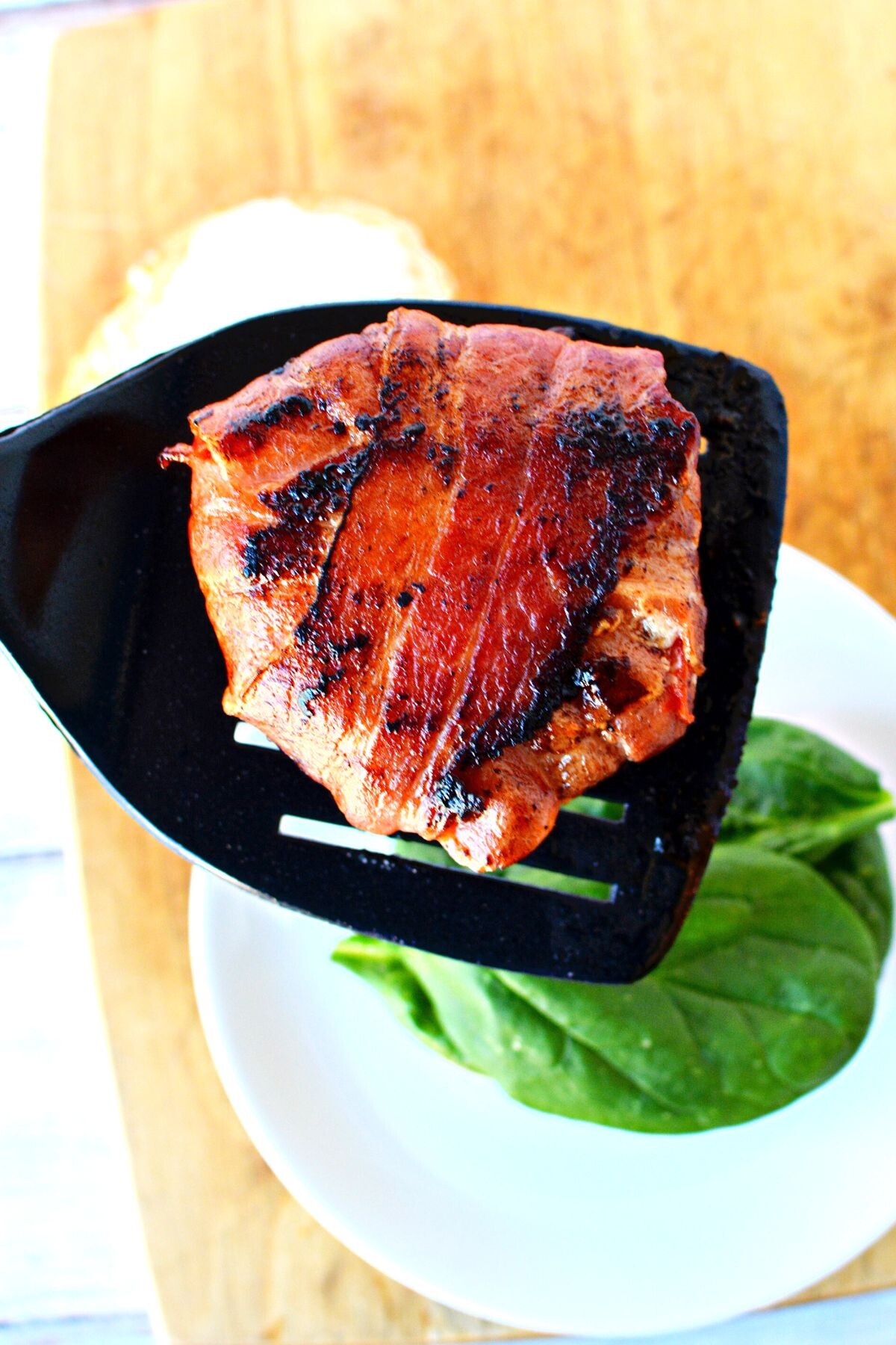 bacon wrapped tomato slices on a spatula.