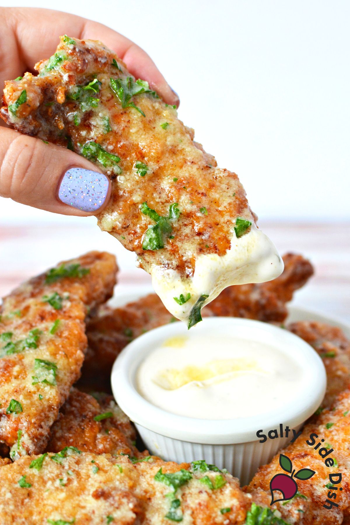 Garlic Parmesan Chicken Tenders being dipped into ranch.
