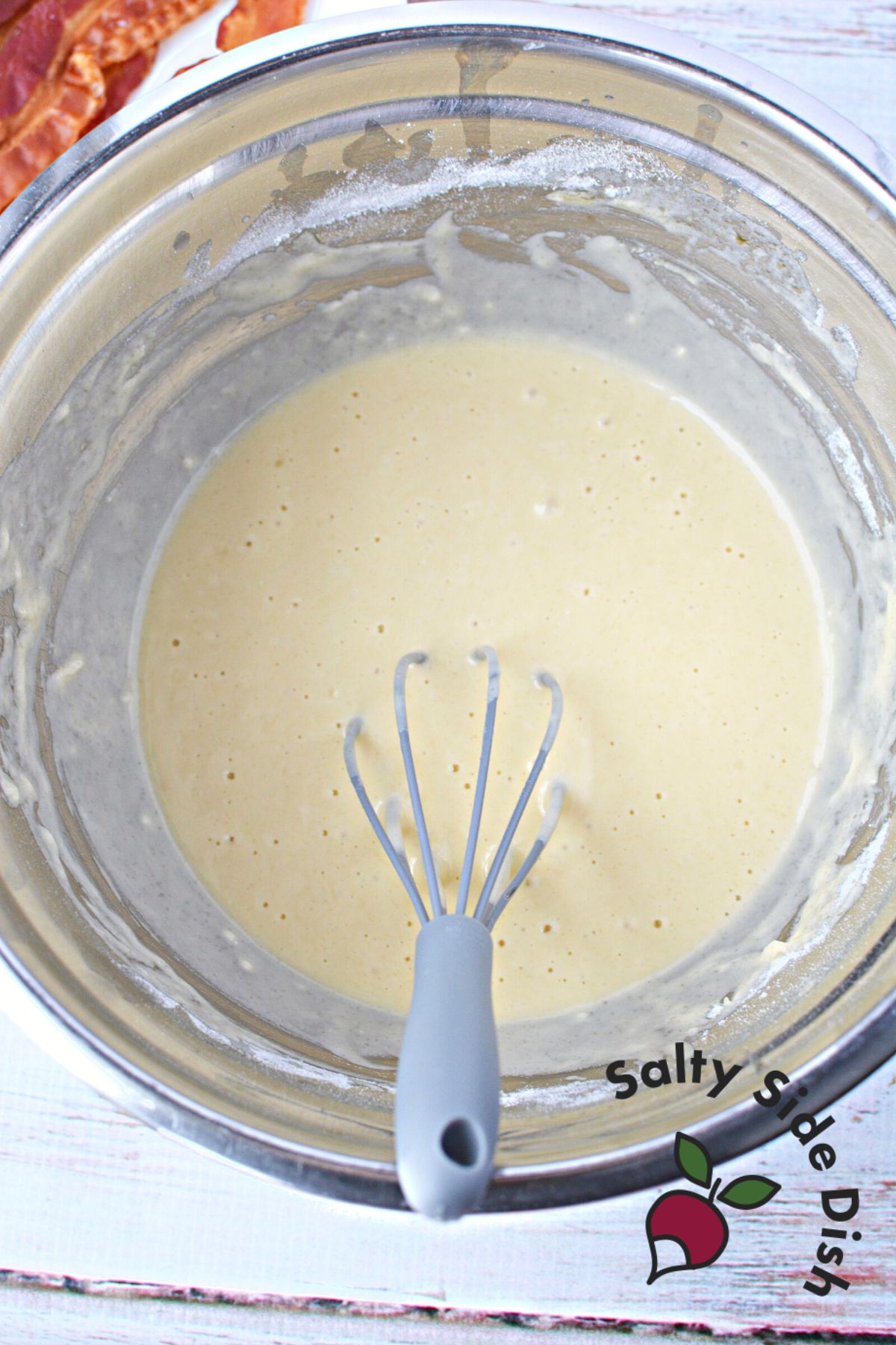 preparing pancake batter in a bowl with a whisk.