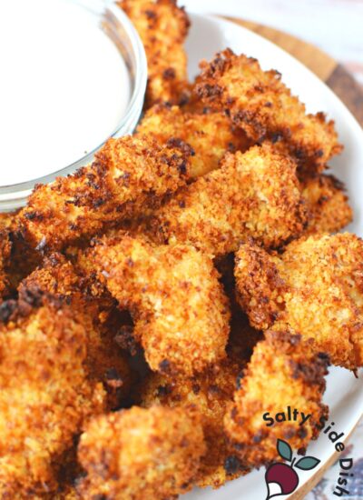 pile of popcorn chicken on a plate with ranch dressing.