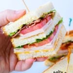 holding a chicken club sandwich.