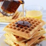 pouring syrup over stack of homemade waffles.