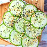 9 pieces of cucumber lined up on a cream cheese piece of bread.
