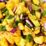 A vibrant bowl of Pineapple Mango Fruit Salad with fresh pineapple, mango, corn, red onion, jalapeno, and cilantro.