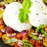 fresh burrata salad recipe on a plate with cheese, tomatoes, basil, and red onions.