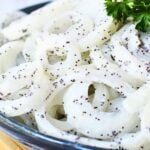 inexpensive side dish to serve at a potluck, this sliced white onion salad is on a serving plate.