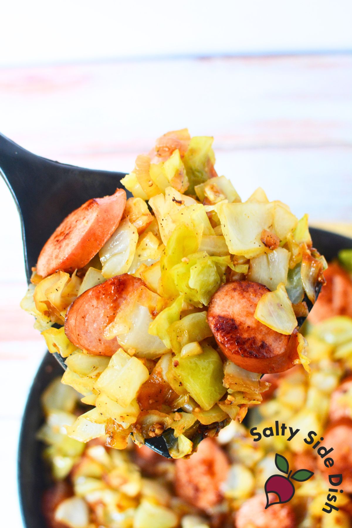 spoon full of fried cabbage and sausage. 