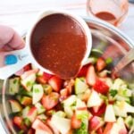 adding cup of dressing onto apples.