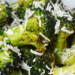 cooked broccoli on a white plate with sprinkled shredded parmesan cheese