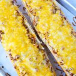 2 pieces of french bread with sloppy joe and cheese on top.