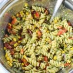 combining pasta and sauce for salad recipe.