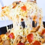 serving tater tot pepperoni pizza casserole being lifted with tons of cheese.