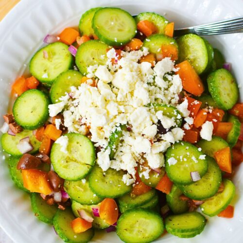 Cucumber slices on a white plate with all the feta cheese.
