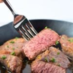Fork holding a medium-cooked piece of juicy broiled steak